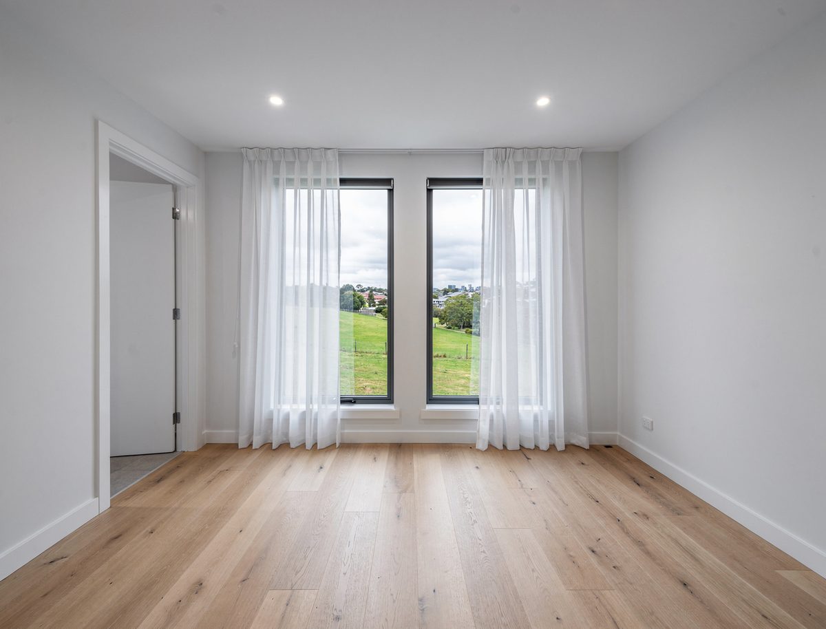 Spacious vacant master bedroom with freshly painted white walls, sheer curtains and rural views in Aintree