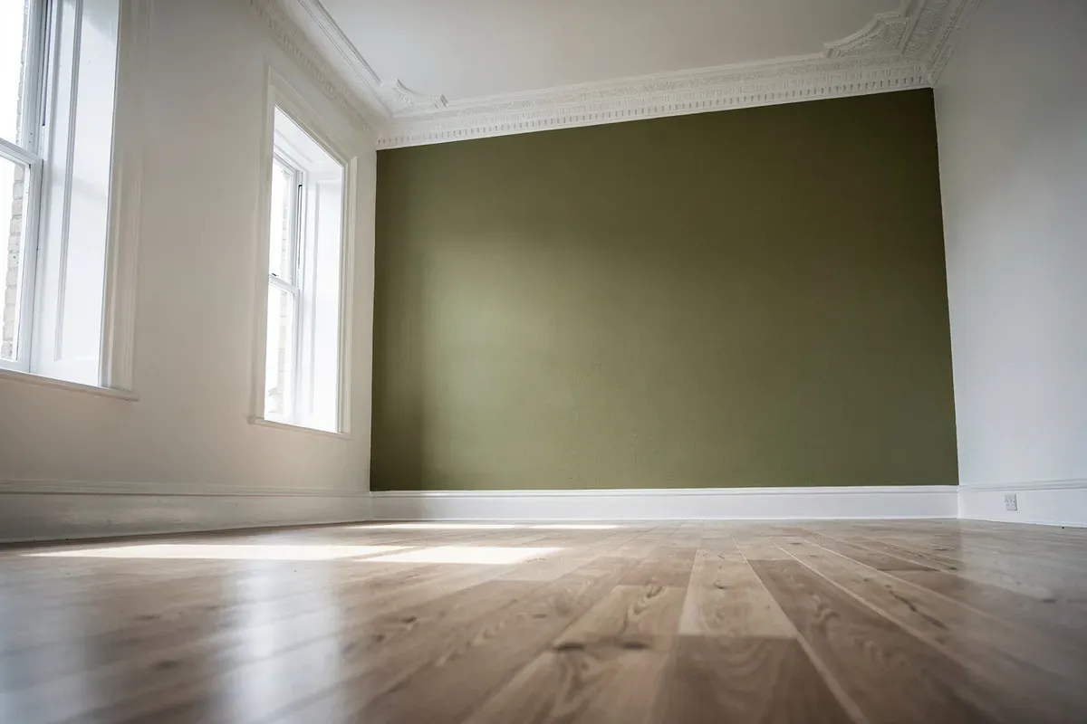 Renovated Edwardian room with olive green feature wall and timber floors