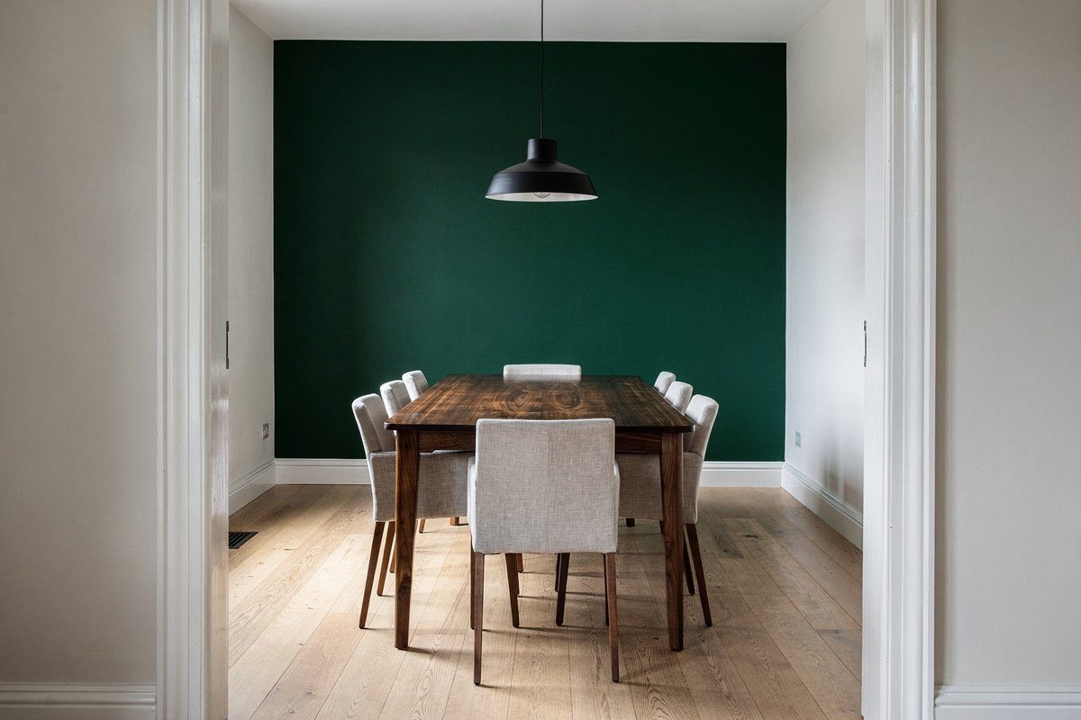 Dining room with forest green feature wall, walnut dining table, linen chairs and black pendant light in a renovated Williamstown home